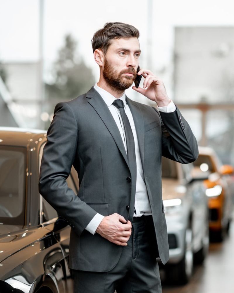 businessman-with-phone-in-the-car-showroom-Z4GX4UW-e1741905609723.jpg